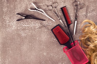 Açık kahverengi arka planda kuaför aletleri. Altın bukleler ve düz yatakta pembe taraklar, metin için yer