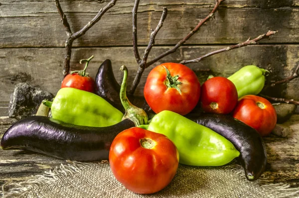 Zralé lilek, rajčata a papriky na spálené desek — Stock fotografie