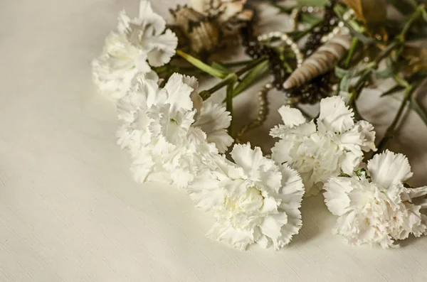Bouquet di grandi garofani bianchi con conchiglie e perline coperte di panno leggero — Foto Stock