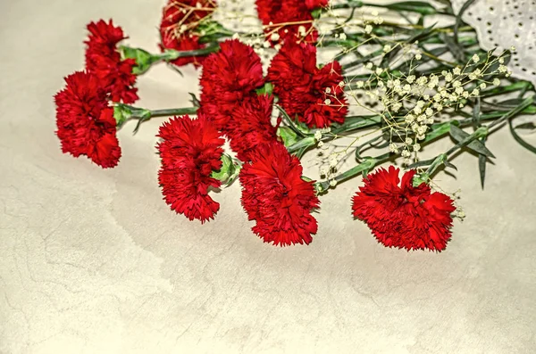 Strauß großer roter Nelken mit weißen getrockneten kleinen Blüten auf Sperrholz — Stockfoto