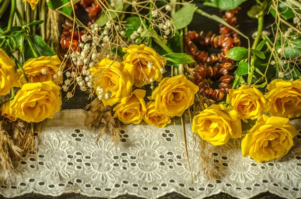 Gelbe Rosen, trockene Äste und weißer Spitzenrand, überzogen mit Bernsteinperlen auf schwarzem Hintergrund — Stockfoto