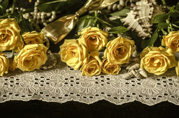 Gelbe Rosen, trockene Zweige weißer Gipsophila, Schilf auf weißem Spitzenrand mit Perlen auf schwarzem Hintergrund — Stockfoto