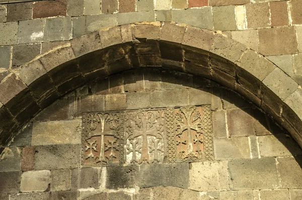 Carved crosses and patterns on the wall under the oval ledge above the entrance gate to the territory of Geghard Monastery in Armenia — Stock Photo, Image