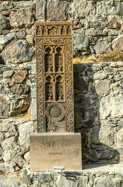 Copie d'un khachkar médiéval sculpté de Jugha, installé le long d'une route escarpée, près d'un mur pavé de pierre menant au monastère de Geghard — Photo