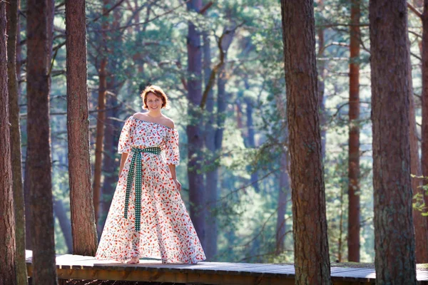 Красивая молодая женщина в белом и длинное платье, позирующее в лесу — стоковое фото