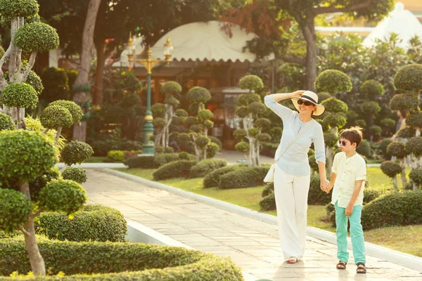 Joven madre y su pequeño hijo caminando en los jardines de bonsáis verdes en Wat Arun — Foto de Stock