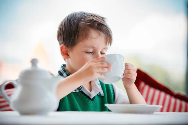 Süßer kleiner Junge trinkt Tee im Café — Stockfoto