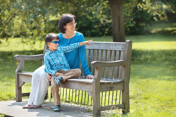 Mutter und ihr kleiner Sohn sitzen auf einer Bank — Stockfoto