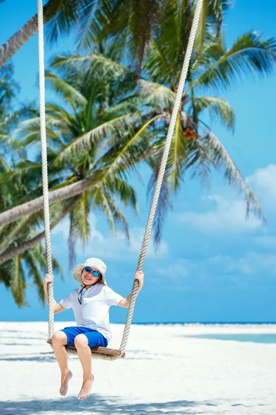 Cute boy having fun swinging at tropical island beach — Stock Photo, Image