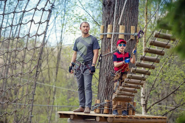 Menino bonito e seu pai aproveitando o tempo no parque de aventura de escalada — Fotografia de Stock