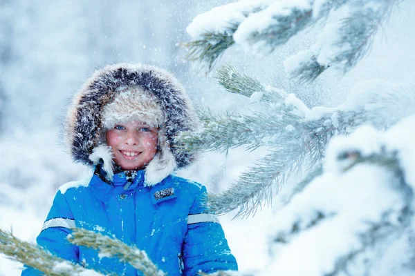 Bonito menino vestindo roupas quentes brincando na floresta de inverno — Fotografia de Stock