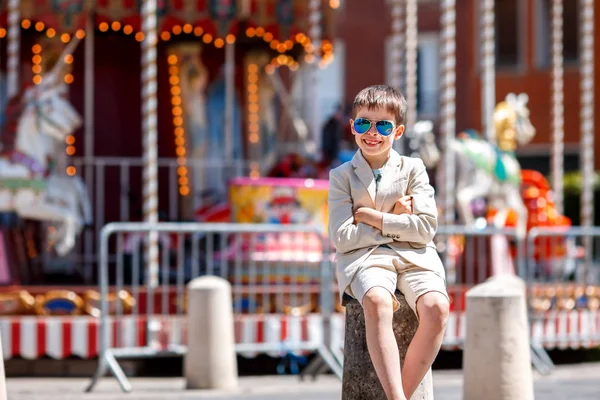 Niño con estilo en un bonito traje y gafas cerca del tradicional tiovivo francés —  Fotos de Stock