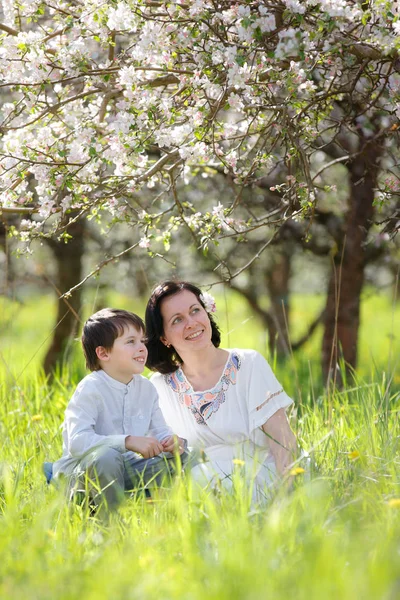 Jeune femme et son enfant se reposent au printemps jardin de pommes — Photo