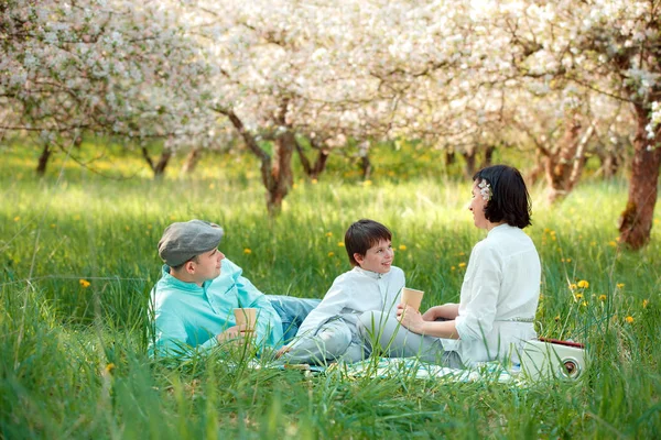 Junge Familie picknickt im blühenden Apfelgarten — Stockfoto