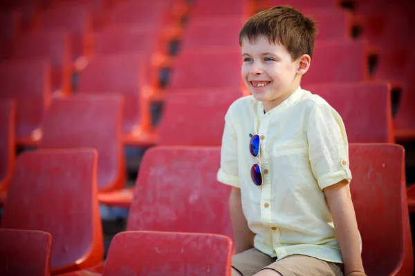 Söt liten pojke sitter på en tribune — Stockfoto