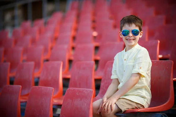 Χαριτωμένο μικρό αγόρι κάθεται σε ένα tribune — Φωτογραφία Αρχείου