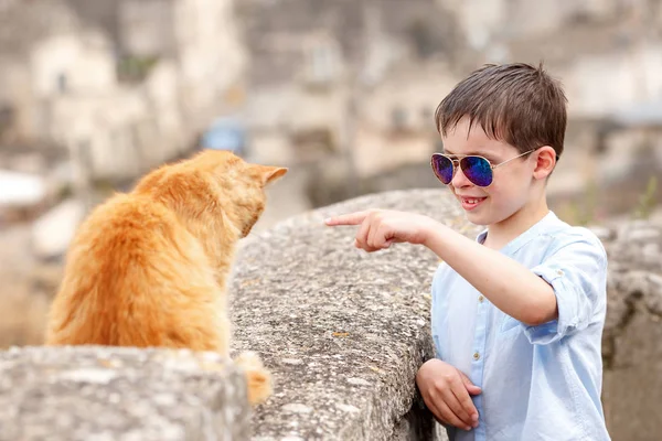 Lindo niño conoció a un gato mientras caminaba en la típica ciudad italiana —  Fotos de Stock