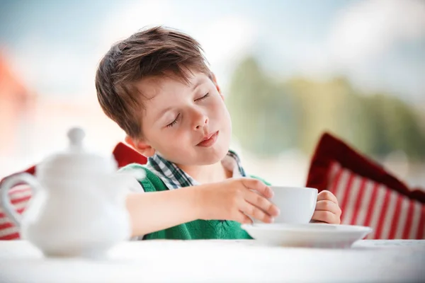 Bonito menino bebendo chá no café — Fotografia de Stock