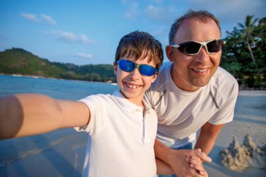 Sevimli küçük çocuk ve babası selfie egzotik adada tropikal plajda yapma