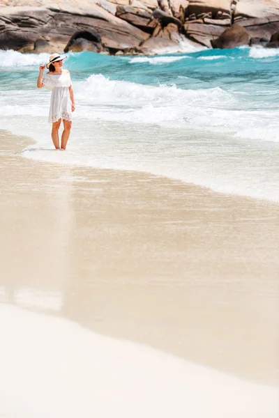 Wanita bergaun putih berjalan di pantai — Stok Foto