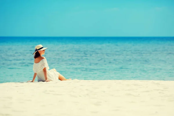 Femeie tânără în rochie albă și pălărie întinsă pe nisipul plajei tropicale având timp de vară minunat — Fotografie, imagine de stoc