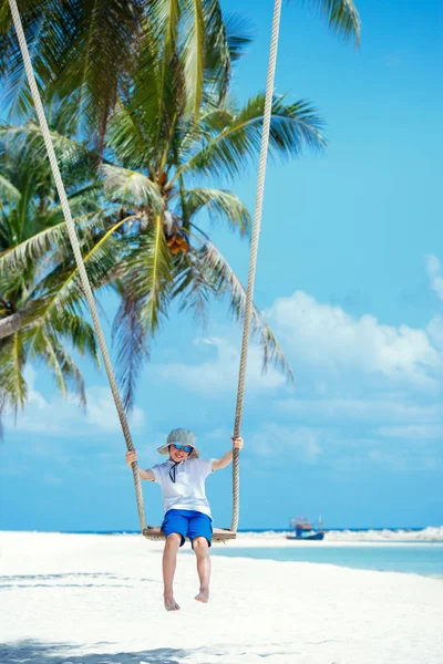 Leuke jongen plezier swingen op tropische eiland strand — Stockfoto