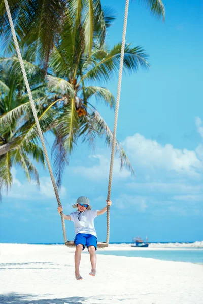 Carino ragazzo avendo divertente oscillazione a tropicale isola spiaggia — Foto Stock