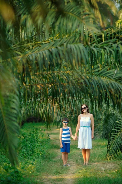 Mujer joven y su pequeño hijo caminando en el bosque tropical — Foto de Stock