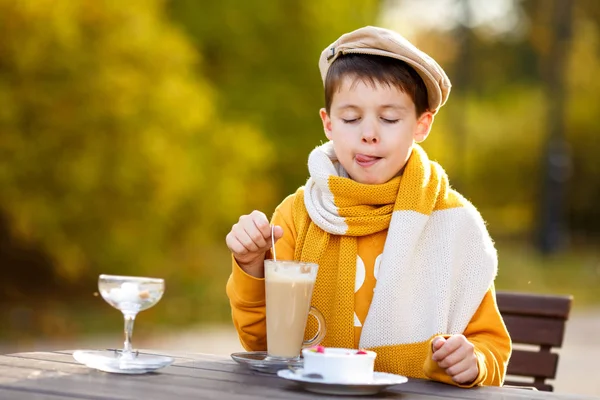 Cute little boy drinking hot chocolate in outdoor cafe — Stock Photo, Image