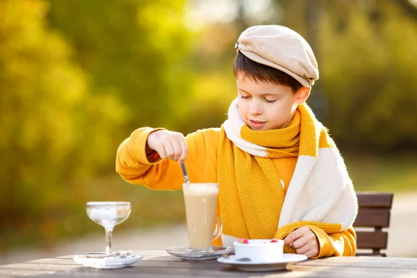 Cute little boy drinking hot chocolate in outdoor cafe — Stock Photo, Image