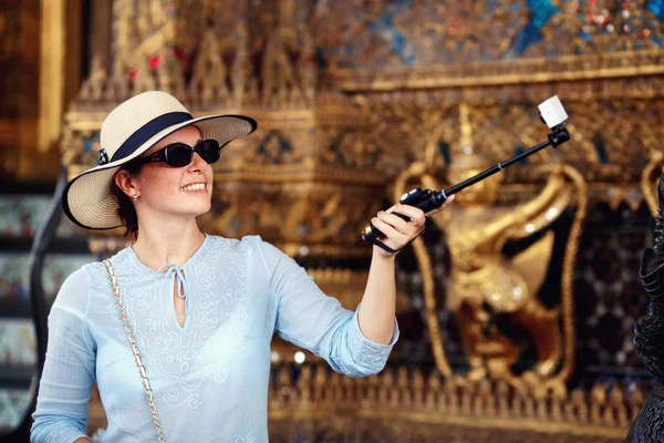 Молода жінка в сонцезахисних окулярах робить селфі з тайським храмом — стокове фото