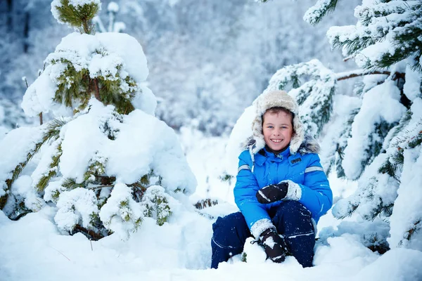 Bonito menino vestindo roupas quentes brincando na floresta de inverno — Fotografia de Stock