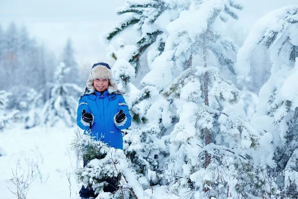 Lindo niño usando ropa de abrigo jugando en el bosque de invierno —  Fotos de Stock