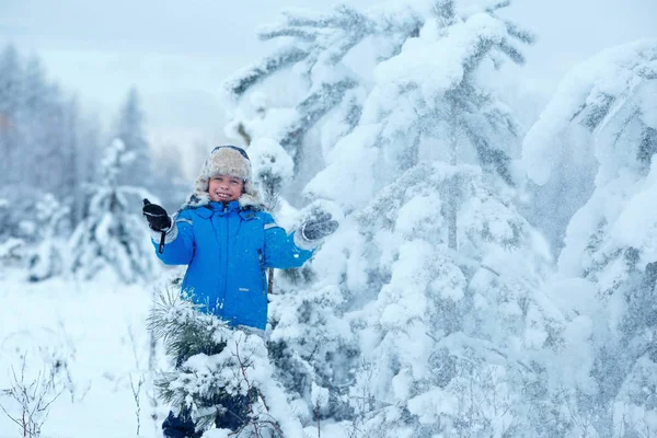 Lindo niño usando ropa de abrigo jugando en el bosque de invierno — Foto de Stock