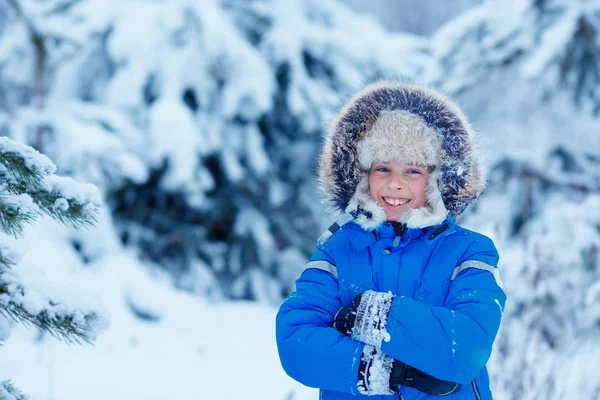 Милый маленький мальчик в теплой одежде играет в зимнем лесу — стоковое фото
