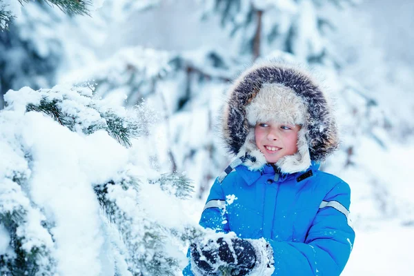 Cute little boy wearing warm clothes playing on winter forest — Stock Photo, Image
