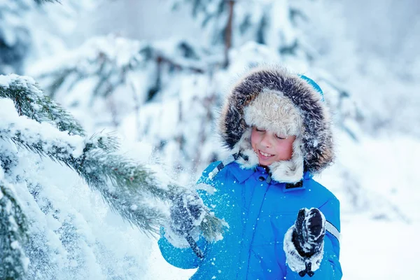 Bonito menino vestindo roupas quentes brincando na floresta de inverno — Fotografia de Stock