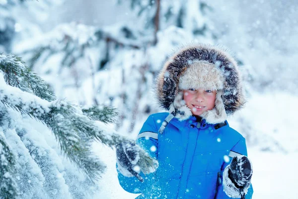 Bonito menino vestindo roupas quentes brincando na floresta de inverno — Fotografia de Stock