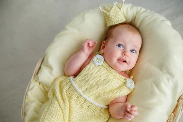 Newborn baby girl lying in a basket with crown and yellow bodysuit — Stock Photo, Image