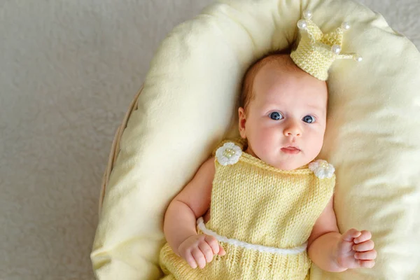 Nyfödd baby flicka liggande i en korg med krona och gul bodysuit — Stockfoto