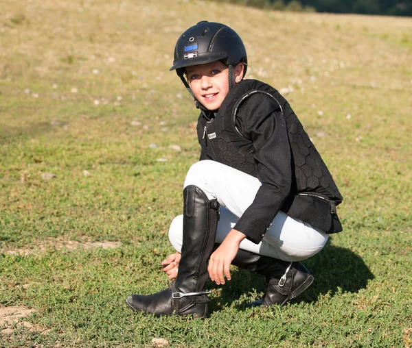 Jovem no capacete preparando esporas antes de mostrar competição de salto — Fotografia de Stock