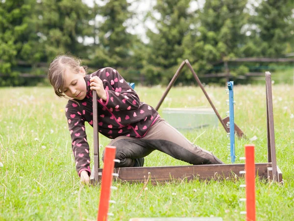 Girl preparing fences for rabbit jumping — Stock Photo, Image