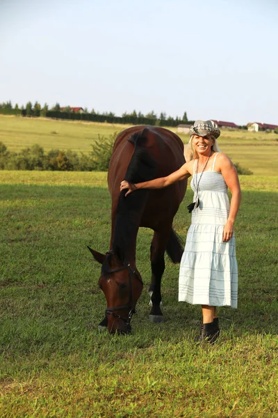 Woman with straw hat with horse in pasture — Stock Photo, Image