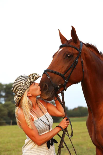 Donna in cappello di paglia baciare il suo cavallo — Foto Stock