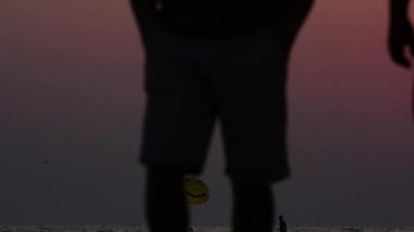 Akşam yürüyüş kıyı boyunca. Gün batımında siluetleri. Bir grup insan. Akşam sahilde yürümek. Günbatımında bir yürüyüş. Yaz sahil. Islak kum üzerinde yürüme. Aile. Çocuklar. Hafta sonu