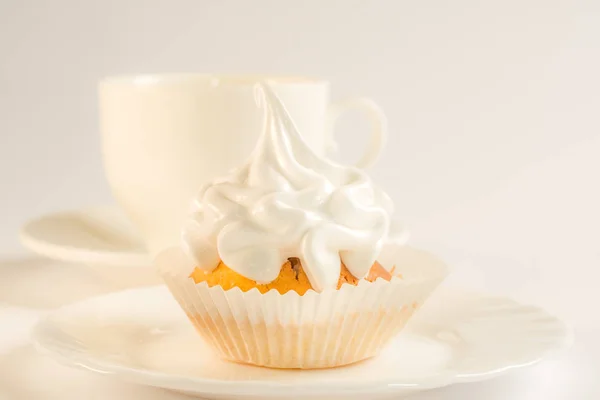 Cupcake mit weißem Zuckerguss auf einem Teller und einer Tasse Tee. süßes Dessert mit weißer Glasur in Nahaufnahme. lizenzfreie Stockbilder