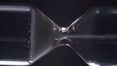 Siyah arka planda kum saatini yakın plan çeviriyorum. Zaman kavramı.