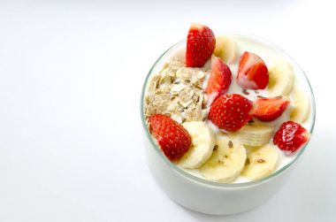 Cam kabı ile yulaf gevreği çilek, muz, keten tohumu beyaz bir arka plan üzerinde beyaz ev yapımı yoğurt dolu. Kahvaltı detoks. Kopya alanı