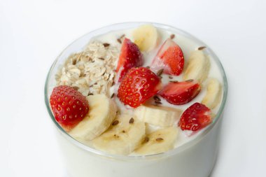 Detoks menü - beyaz yoğurtla çilek, muz, yulaf gevreği, beyaz bir arka plan üzerinde keten tohumu Keten tohumu yakın çekim ile serpilir 