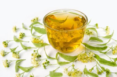 Ihlamur soğuk limon çiçekleri ile şeffaf bir fincan çay. Beyaz arka plan. Yan görünüm